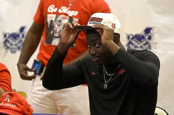 Quincy Rhodes puts on a hat after signing with Arkansas during a ceremony Wednesday, Dec. 21, 2022, in North Little Rock.