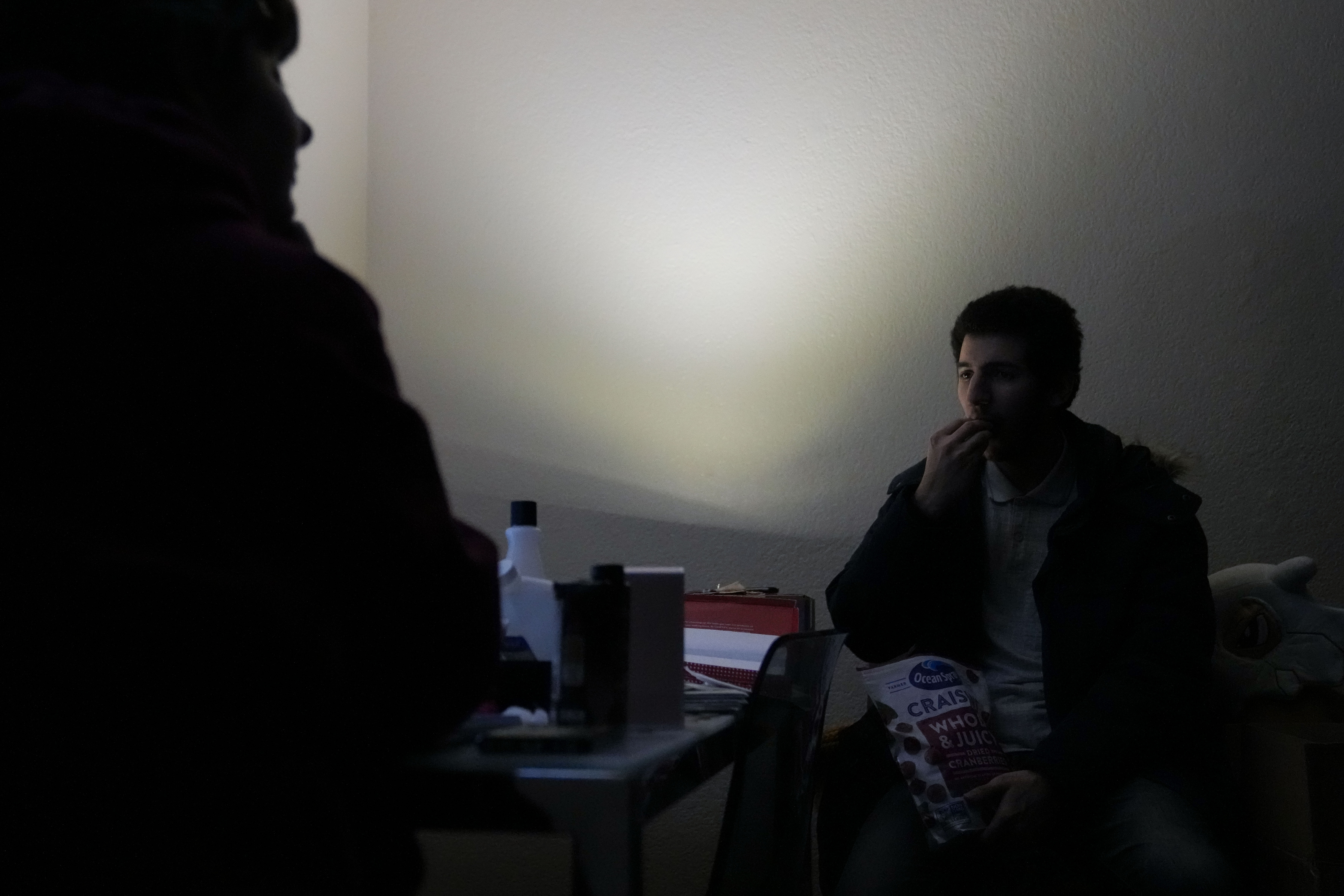 Jarod Valentin, right, eats dried cranberries inside his apartment after an earthquake in Rio Dell, Calif., Tuesday, Dec. 20, 2022. A strong earthquake shook a rural stretch of Northern California early Tuesday, jolting residents awake, cutting off power to 70,000 people, and damaging some buildings and a roadway, officials said. Two injuries were reported. (AP Photo/Godofredo A. Vásquez)