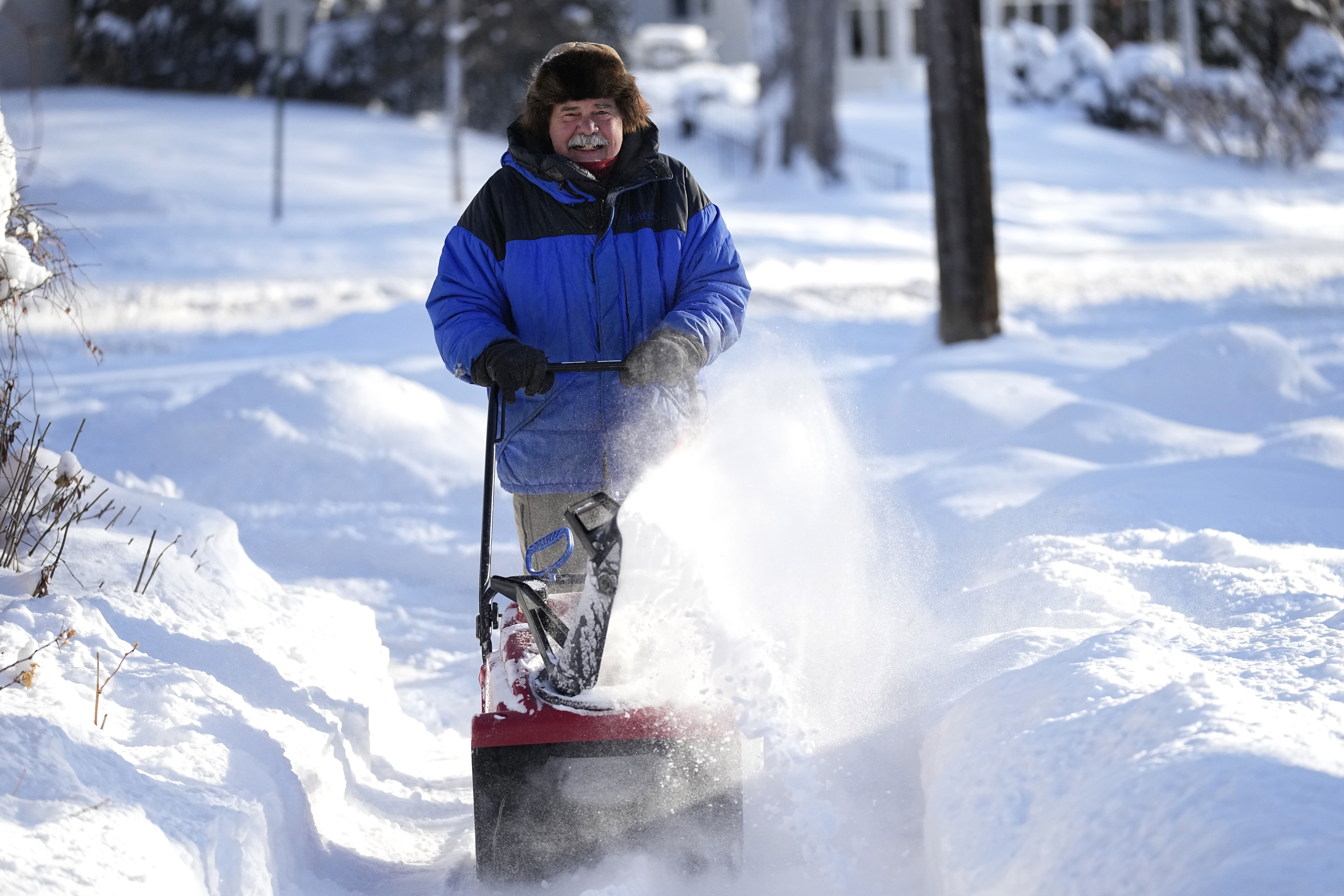 A man clears snow off a sidewalk Thursday, Dec. 22, 2022, in Minneapolis. (AP Photo/Abbie Parr)