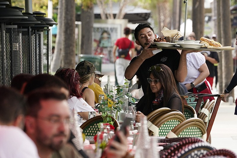 A waiter delivers food to patrons at a restaurant in January at Miami Beach, Fla. An increase in services spending in November, led by restaurants and accommodation, offset a decline in spending on merchandise, the Commerce Department reported Friday.
(AP)