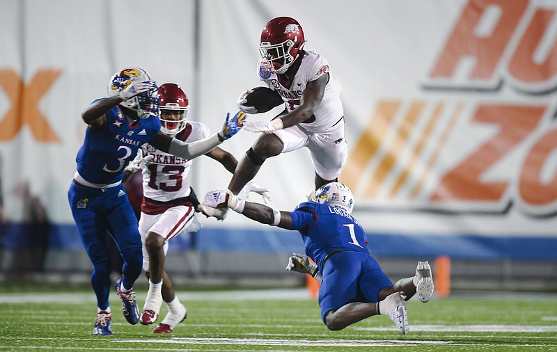 Arkansas running back Rashod Dubinion (center) leaps over Kansas safety Kenny Logan during the second quarter of the Liberty Bowl against Kansas on Wednesday at Simmons Bank Liberty Stadium in Memphis. Dubinion finished with 112 yards and 2 touchdowns on 20 carries in the Razorbacks’ 55-53 win in three overtimes.
(NWA Democrat-Gazette/Charlie Kaijo)