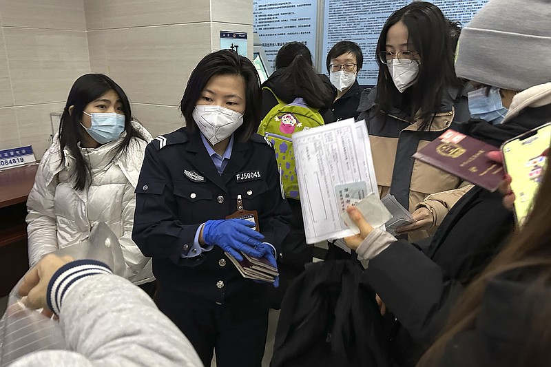 An officer collects passports from residents for renewal and reapplication Wednesday at a community police station in Beijing as China resumes issuing passports for tourism ahead of next month’s Lunar New Year celebrations.
(AP/Ng Han Guan)