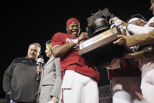 Arkansas quarterback KJ Jefferson (center) holds the Liberty Bowl trophy following the Razorbacks' 55-53 victory over Kansas in three overtimes on Wednesday, Dec. 28, 2022, in Memphis, Tenn.