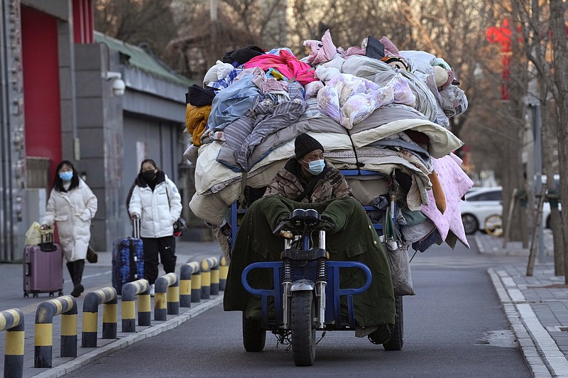 A man wearing a mask transports used quilts and other scavenged cloth material Friday in Beijing. China is on a bumpy road back to normal life as schools, shopping malls and restaurants fill up again following the abrupt end of some of the world’s most severe restrictions even as hospitals are swamped with feverish, wheezing COVID-19 patients.
(AP/Ng Han Guan)