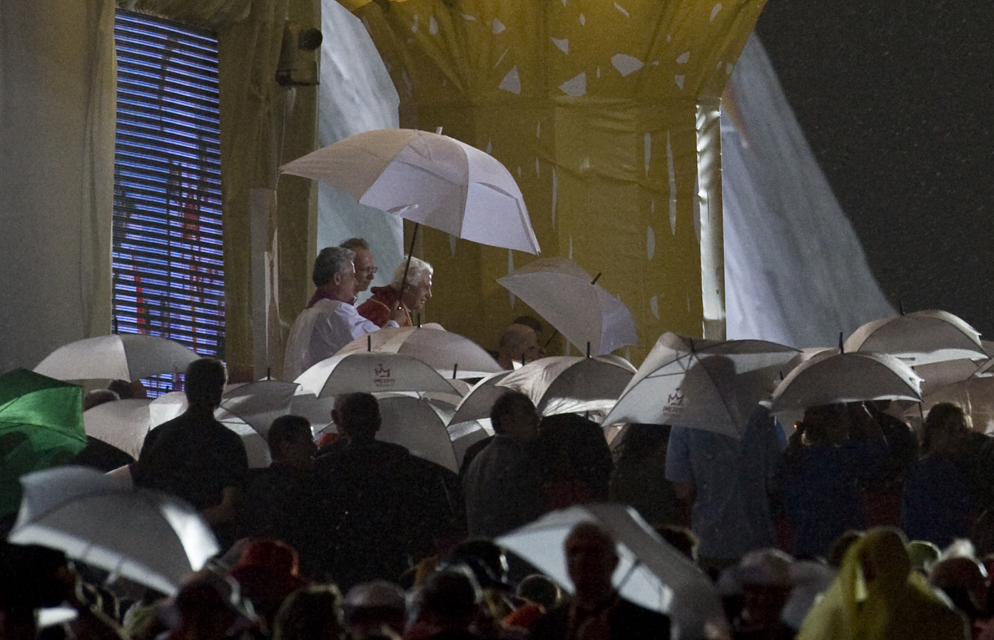 FILE - Pope Benedict XVI is protected from the rain by an umbrella in Cuatro Vientos, near to Madrid, Spain, on Saturday, Aug. 20, 2011. He was the reluctant pope, a shy bookworm who preferred solitary walks in the Alps and Mozart piano concertos to the public glare and majesty of Vatican pageantry. When Cardinal Joseph Ratzinger became Pope Benedict XVI and was thrust into the footsteps of his beloved and charismatic predecessor, he said he felt a guillotine had come down on him. The Vatican announced Saturday Dec. 31, 2022 that Benedict, the former Joseph Ratzinger, had died at age 95. (AP Photo/Alvaro Barrientos, File)