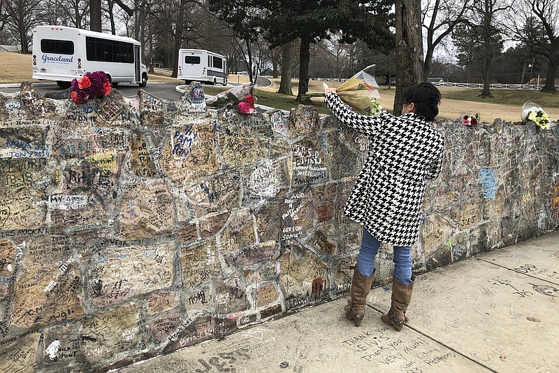 A fan places a bouquet of flowers Friday on the stone wall outside Graceland in Memphis.
(AP/Adrian Sainz)