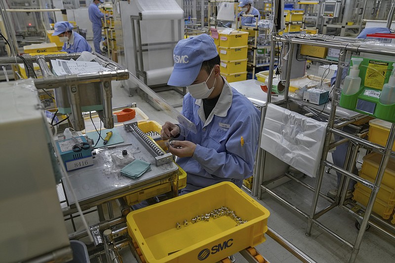 Workers wearing face masks assembly machinery parts at SMC, a Japanese pneumatic engineering company factory in Beijing on Jan. 10, 2023. (AP Photo/Andy Wong)