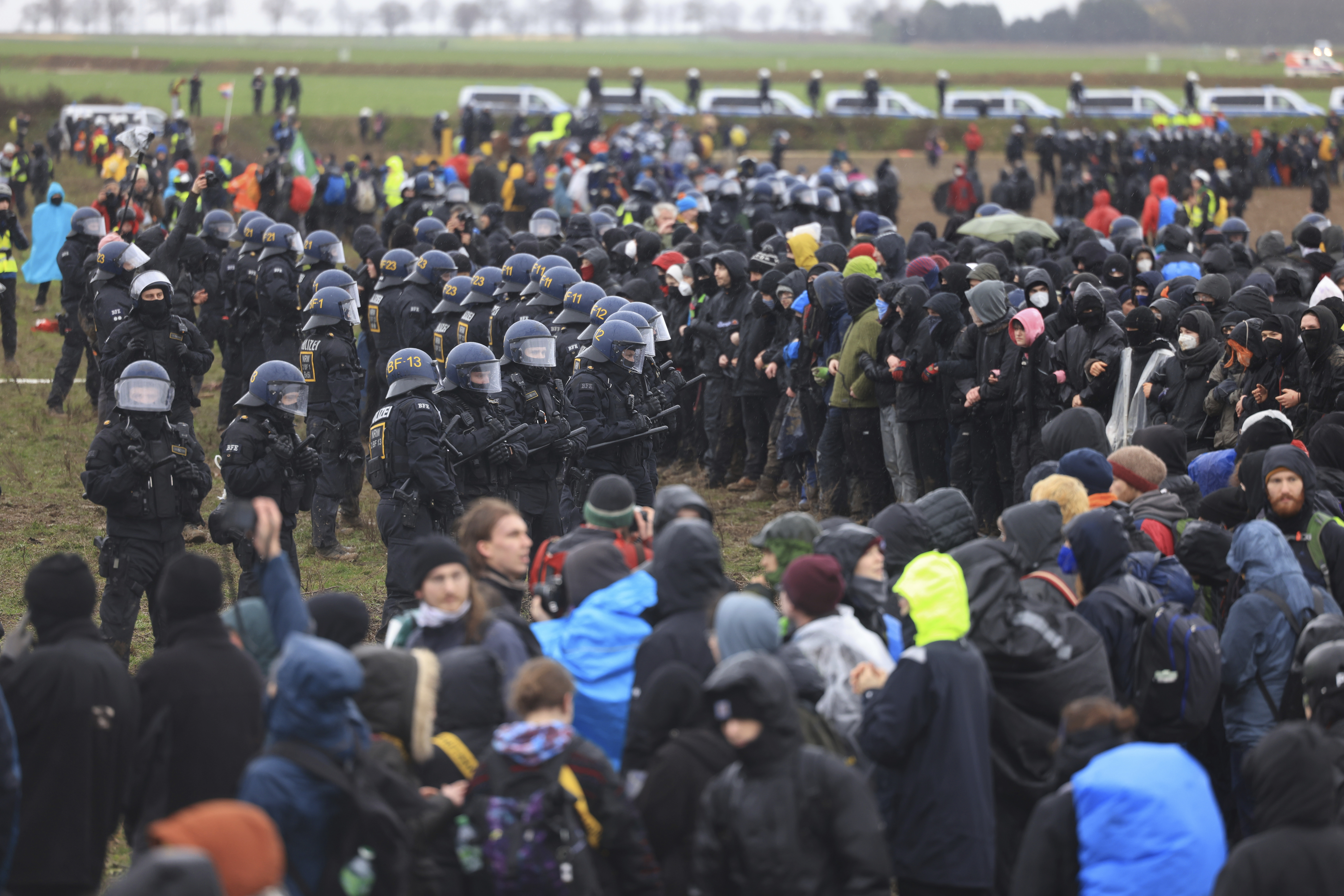 Police officers form a line to block demonstrators on the edge of the opencast lignite mine Garzweiler at the village Luetzerath near Erkelenz, Germany, Saturday, Jan. 14, 2023. ( Oliver Berg/dpa via AP)