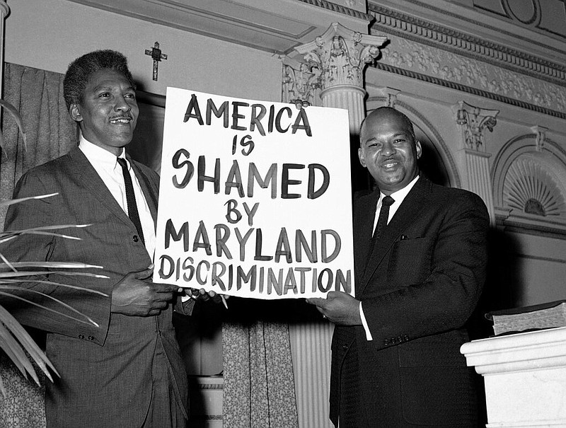 Bayard Rustin (left) of New York City and the Rev. Logan Kearse of Baltimore pose at Kearse's church in this Nov. 18, 1961 file photo. The two were showing one of the signs carried by demonstrators who staged sit-ins at Baltimore restaurants to protest segregation. Rustin was the former secretary to the Rev. Martin Luther King Jr., and Kearse's Cornerstone Baptist Church was the starting point for the Baltimore sit-ins. (AP/William A. Smith)