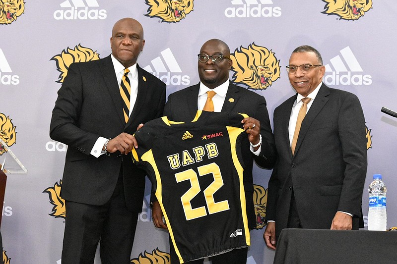 UAPB Athletic Director Chris Robinson, left, and Chancellor Laurence B. Alexander, right, present a jersey to new football head Coach Alonzo Hampton toward the end of Tuesday's news conference. (Pine Bluff Commercial/I.C. Murrell)