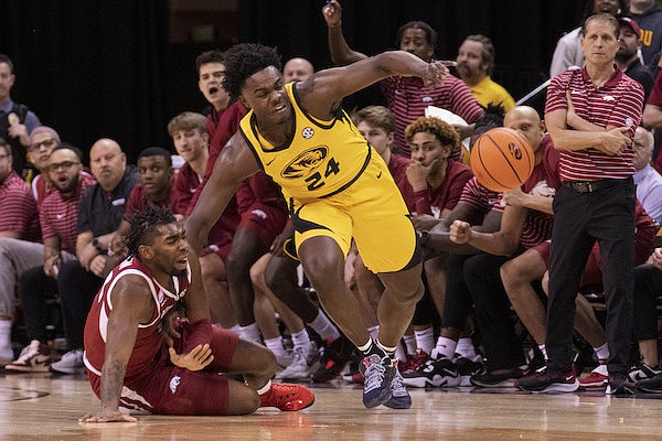 Arkansas' Kamani Johnson, left, pulls Missouri's Kobe Brown, right, to the court during the first half of an NCAA college basketball game Wednesday, Jan. 18, 2023, in Columbia, Mo. (AP Photo/L.G. Patterson)