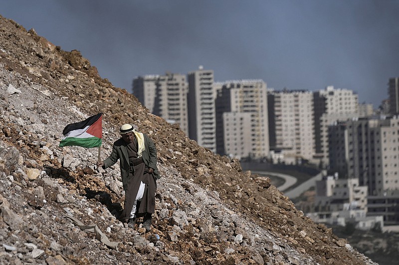A protester carries a Palestinian flag Friday near the West Bank city of Ramallah during a demonstration against a new Israeli settlement in the village of Qalandia. The protest was held as Israelis dismantled an unauthorized Israeli settler outpost near Nablus in the northern West Bank.
(AP/Majdi Mohammed)