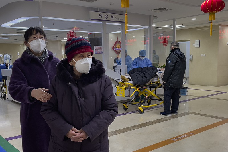 An elderly woman wearing a face mask is accompanied by a relative as patients are checked after arriving in the emergency hall of a hospital in Beijing, Thursday, Jan. 19, 2023. China on Thursday accused "some Western media" of bias, smears and political manipulation in their coverage of China's abrupt ending of its strict "zero-COVID" policy, as it issued a vigorous defense of actions taken to prepare for the change of strategy. (AP Photo/Andy Wong)