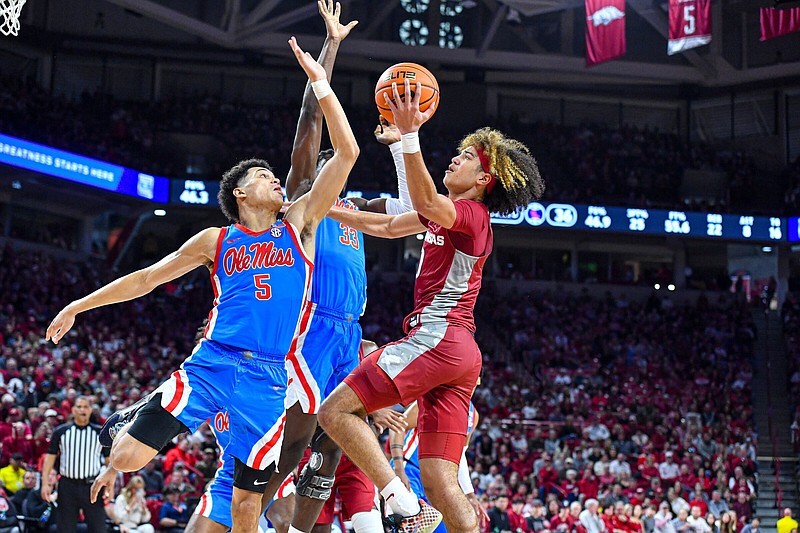 Arkansas guard Anthony Black (right) shoots as Ole Miss guard James White (5) and forward Josh Mballa (33) defend during the second half Saturday at Walton Arena in Fayetteville. Black had 17 points, 8 assists and 5 steals as the Razorbacks won 69-57, snapping a four-game losing streak. More photos at arkansasonline.com/122omua/
(NWA Democrat-Gazette/Hank Layton)