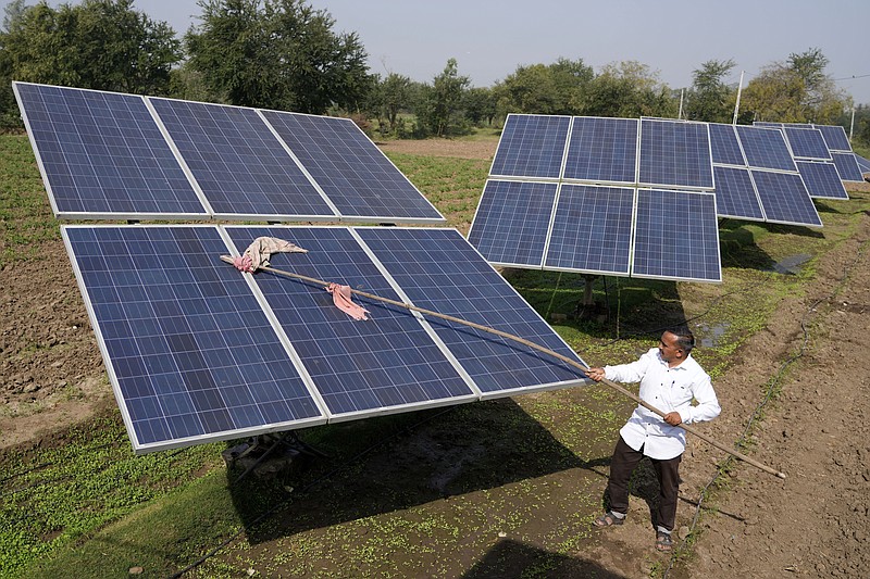 Farmer Pravinbhai Parmar cleans a solar panel installed at a farm in Dhundi village of Kheda district in western Indian Gujarat state, India, Friday, Jan. 13, 2023. Parmar has been using solar power for irrigation and sells the excess electricity to the state's grid to earn additional income. (AP Photo/Ajit Solanki)