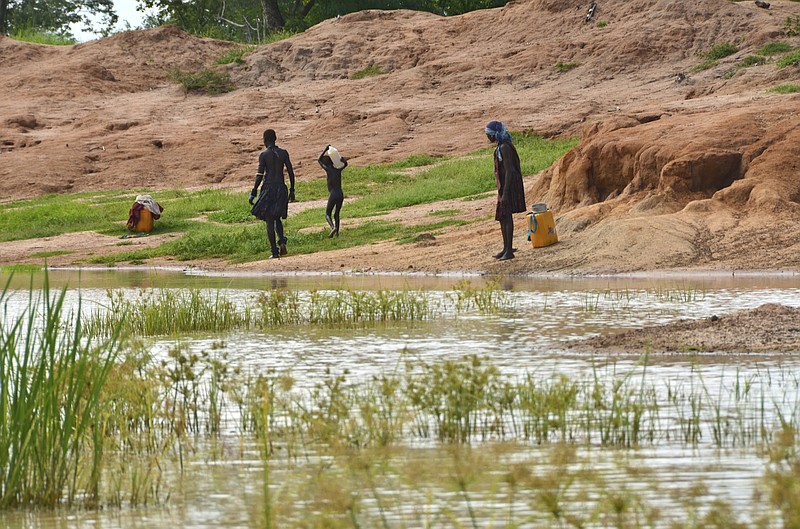 FILE - Children in the town of Terekeka, South Sudan, draw water, Oct. 4, 2017, from a stagnant pond that was once infected with Guinea worm when the town was endemic. The Carter Center said Tuesday, Jan. 24, 2023, that only 13 human cases of Guinea worm disease were reported worldwide in 2022. (AP Photo/Mariah Quesada, File)