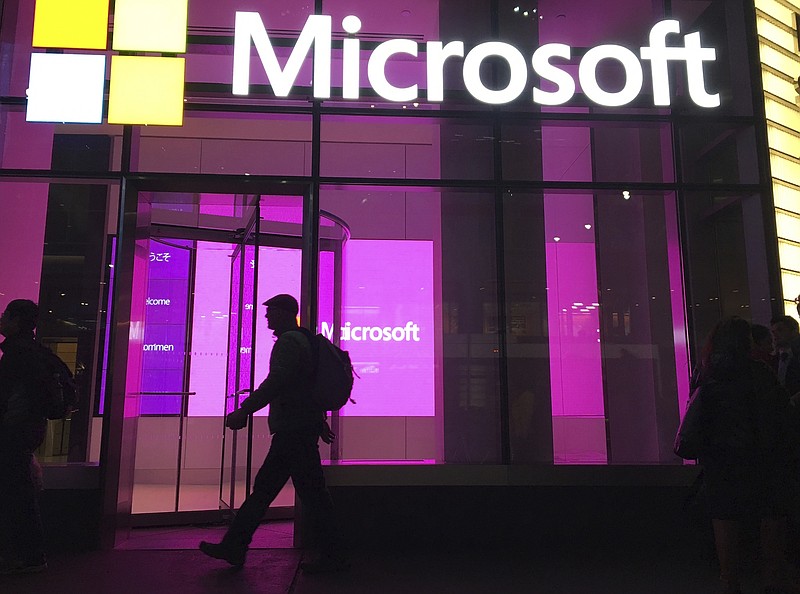FILE - People walk past a Microsoft office in New York, Nov. 10, 2016. On Tuesday, Jan. 24, 2023, Microsoft reported a 12% drop in profit for the October-December 2022 quarter, reflecting the economic uncertainty it said led to its decision to cut 10,000 workers. (AP Photo/Swayne B. Hall, File)