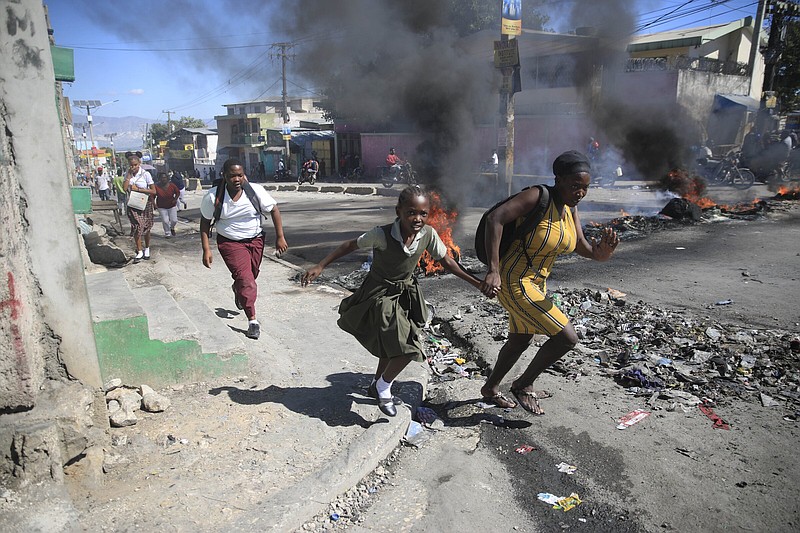 A woman with her daughter runs past a barricade that was set up by members of the police as they protest bad police governance Thursday in Port-au-Prince, Haiti.
(AP/Odelyn Joseph)
