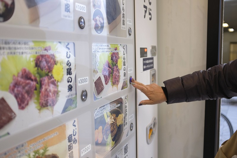 CORRECTS THE PHOTOGRAPHER'S NAME TO KWIYEON HA - A customer purchases whale meat from a vending machine at Kyodo Senpaku's unmanned store, Thursday, Jan. 26, 2023, in Yokohama, Japan. The Japanese whaling operator, after struggling for years to promote its controversial products, has found a new way to cultivate clientele and bolster sales: whale meat vending machines. (AP Photo/Kwiyeon Ha)