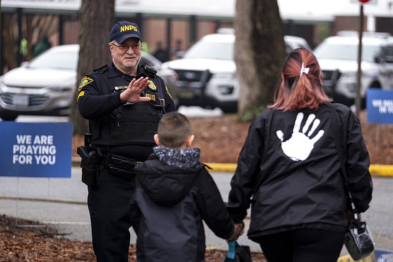 Sgt Jamie Huling of the Newport News Police Department greets students as they return to Richneck Elementary in Newport News, Va., on Monday, Jan. 30, 2023.  The elementary school where a 6-year-old boy shot his teacher reopened Monday with stepped-up security and a new administrator, as nervous parents and students expressed optimism about a return to the classroom. (Billy Schuerman/The Virginian-Pilot via AP)