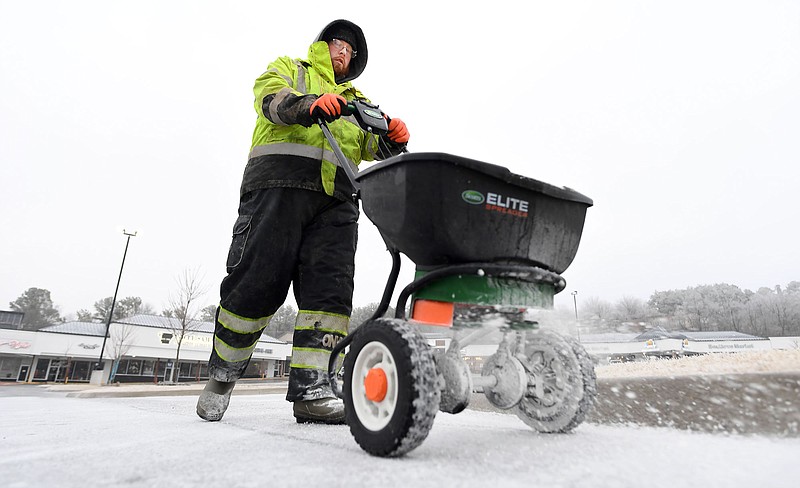 Zach Frost with Pro's Pressure Washing spreads salt Monday, Jan. 30, 2023, in the parking lot at Evelyn Hills in Fayetteville after ice fell overnight. (NWA Democrat-Gazette/Andy Shupe)