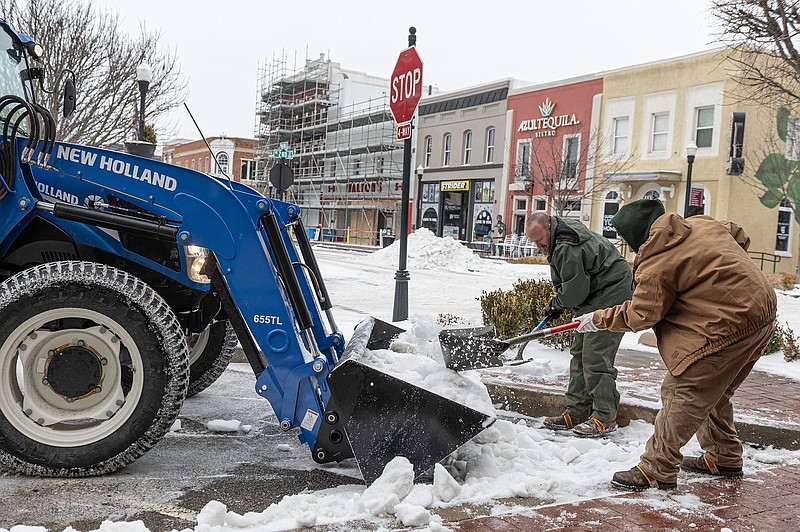 Maria Aleman, in brown, and Geoff Braga both with the Bentonville Parks and Recreation Department work Tuesday, January 31, 2023 to clear the parking spaces around the Bentonville Sqaure of snow, ice and sleet.  (NWA Democrat-Gazette/Spencer Tirey)