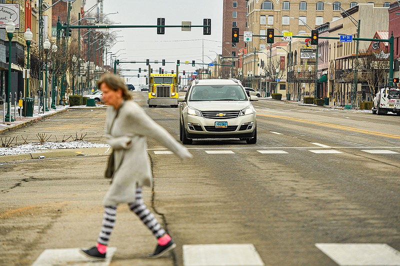 Traffic waits at a red light as a woman crosses Garrison Avenue, Wednesday, Feb. 1, 2023, in downtown Fort Smith. The National Weather Service issued an ice storm warning for the city and other areas in the River Valley until noon today, with up to 3/10 of an inch of ice expected to accumulate. Visit nwaonline.com/photo for today's photo gallery..(NWA Democrat-Gazette/Hank Layton)