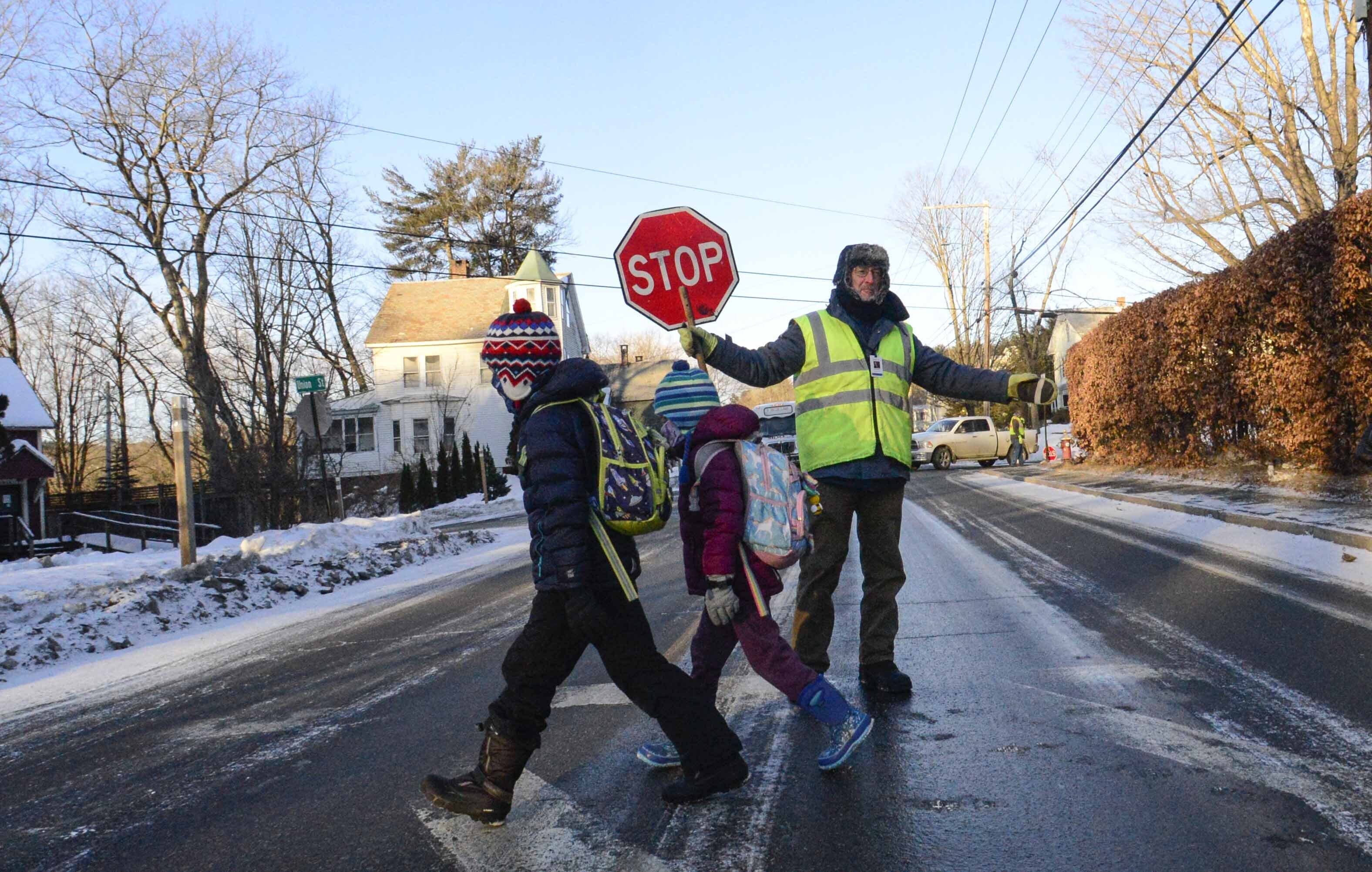 Bundled up, Tom Gilbert, a crossing guard for Windham Southeast Supervisory Union, helps students cross Western Avenue in Brattleboro, Vt., on their way to school on Friday, Feb. 4, 2023. In New England, temperatures began plunging Friday morning. (Kristopher Radder/The Brattleboro Reformer via AP)