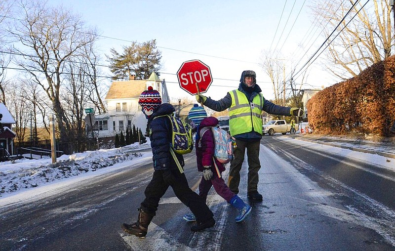 Bundled up, Tom Gilbert, a crossing guard for Windham Southeast Supervisory Union, helps students cross Western Avenue in Brattleboro, Vt., on their way to school on Friday, Feb. 4, 2023. In New England, temperatures began plunging Friday morning. (Kristopher Radder/The Brattleboro Reformer via AP)