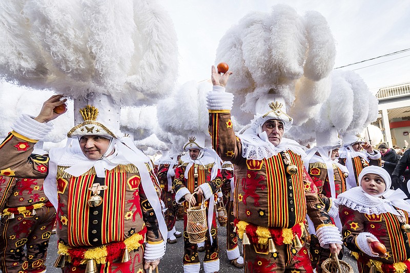 FILE - A Gilles of Binche throws an orange during the Binche carnival, in Binche, Belgium, Tuesday, Feb. 12, 2013. After a COVID-imposed hiatus, artisans are putting finishing touches on elaborate costumes and floats for the renowned Carnival in the Belgian town of Binche, a tradition that brings together young and old and is a welcome moment of celebration after a rough few years. (AP Photo/Geert Vanden Wijngaert, File)