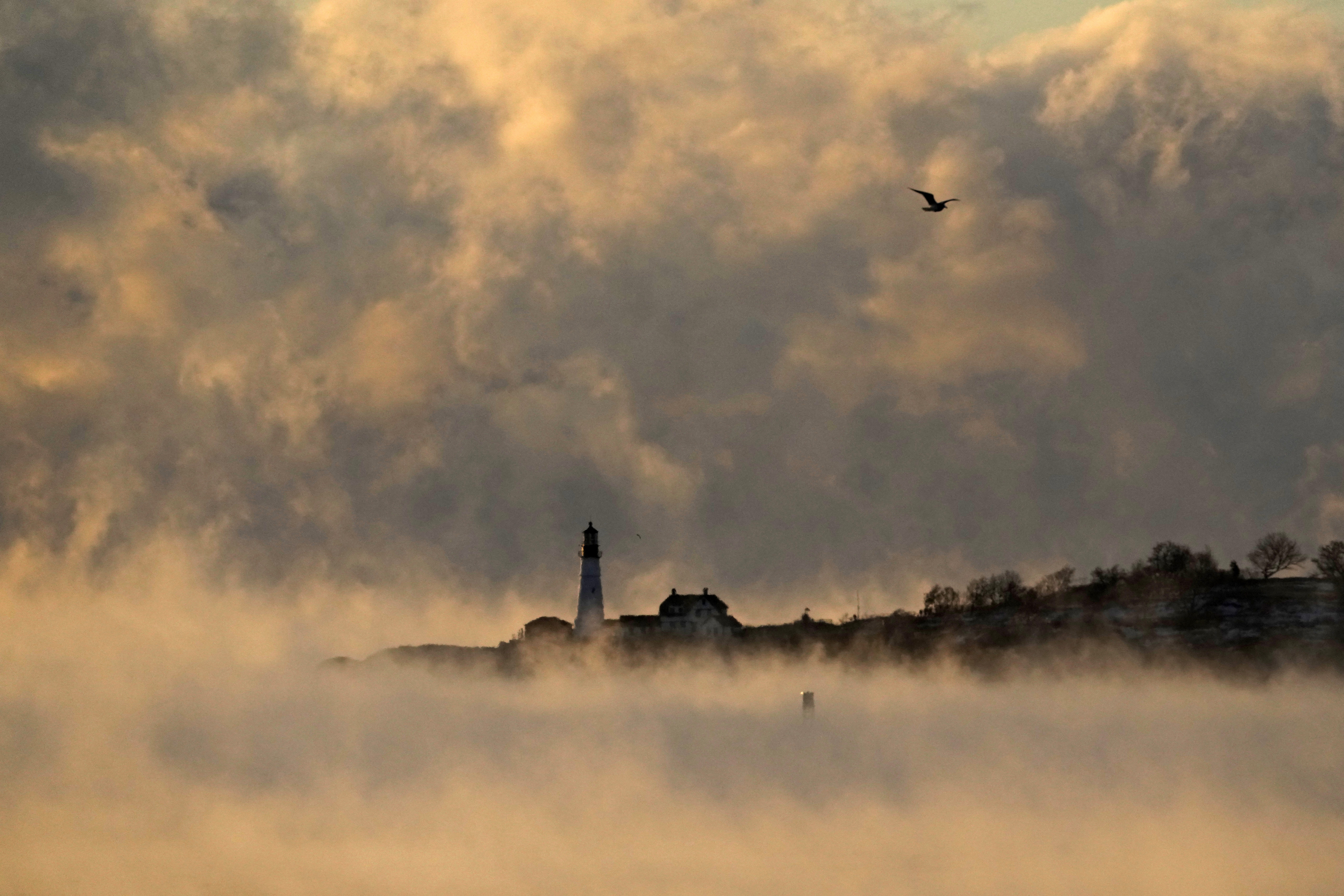 Arctic sea smoke rises from the Atlantic Ocean at Portland Head Light, Saturday, Feb. 4, 2023, in Cape Elizabeth, Maine. The morning temperature was about -10 degrees Fahrenheit. (AP Photo/Robert F. Bukaty)