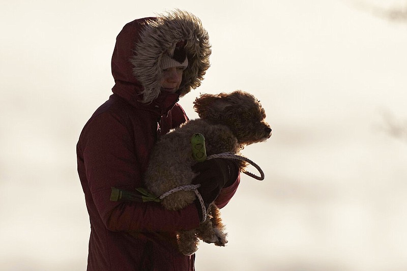 A woman carries her dog in the bitter cold, Saturday, Feb. 4, 2023, in Portland, Maine. The morning temperature was about -10 degrees Fahrenheit. (AP/Robert F. Bukaty)