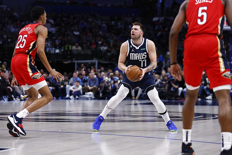 Dallas Mavericks guard Luka Doncic (77) attempts a three-point shot as New Orleans Pelicans guard Trey Murphy III (25) and forward Herbert Jones (5) defend during the second half of an NBA basketball game, Thursday, Feb. 2, 2023, in Dallas. Doncic would leave the game shortly afterwards with a right heel contusion. (AP Photo/Brandon Wade)