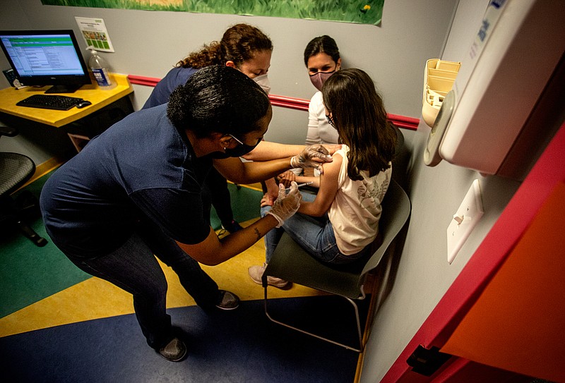 FILE - Middle school student Elise Robinson receives a coronavirus vaccination on May 12, 2021, in Decatur, Ga. A bill passed on Wednesday, Feb, 1 2023, by a Georgia Senate committee would ban public schools, local governments or state agencies from requiring people to get the COVID-19 vaccine before they could attend school or receive government services. (AP Photo/Ron Harris, File)