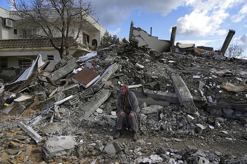A woman sits on the rubble as emergency rescue teams search for people under the remains of destroyed buildings in Nurdagi town on the outskirts of Osmaniye city southern Turkey, Tuesday, Feb. 7, 2023. (AP/Khalil Hamra)