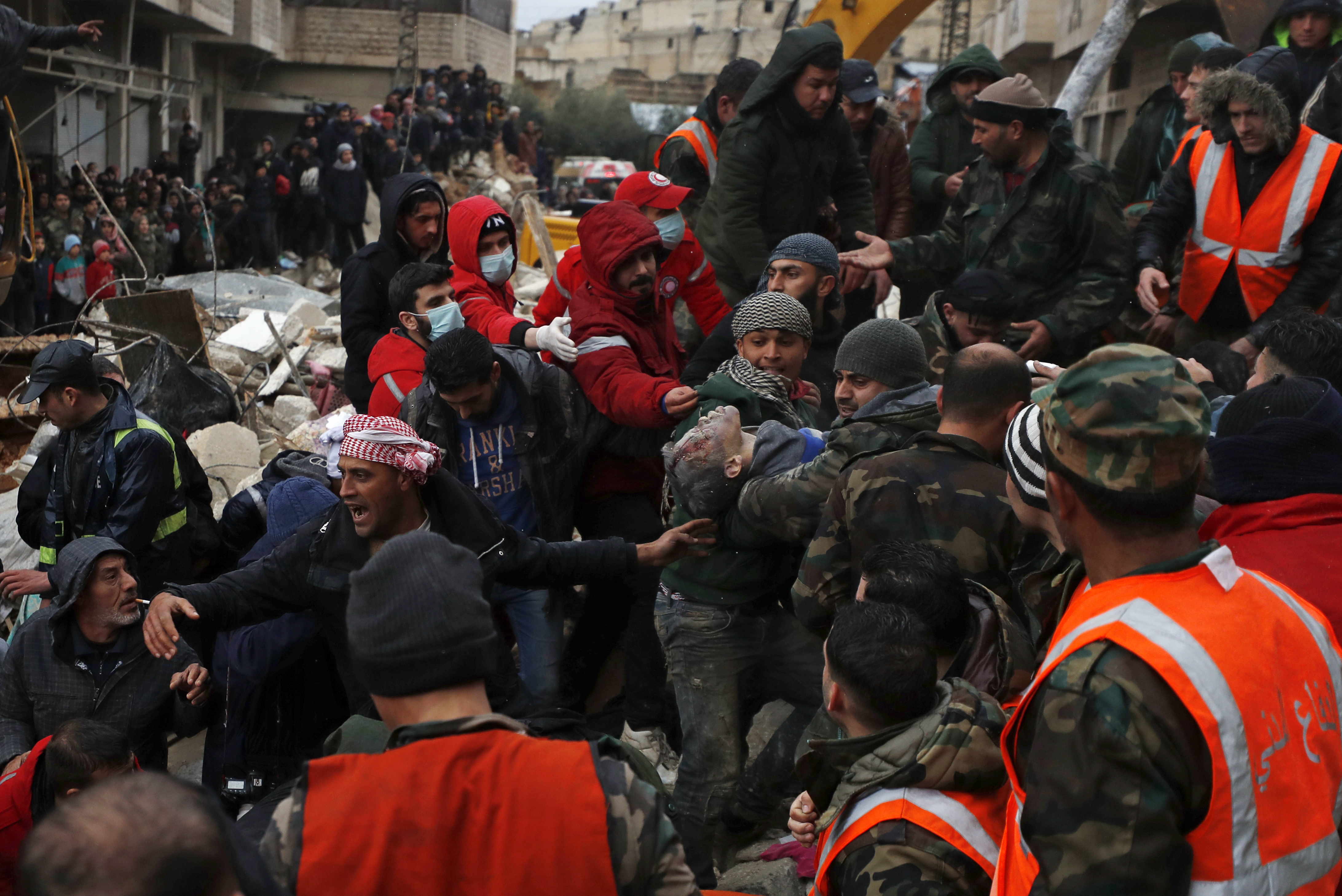 Civil defense workers and security forces carry an earthquake victim as they search through the wreckage of collapsed buildings in Hama, Syria, Monday, Feb. 6, 2023. A powerful earthquake has caused significant damage in southeast Turkey and Syria and many casualties are feared. Damage was reported across several Turkish provinces, and rescue teams were being sent from around the country. (AP Photo/Omar Sanadiki)