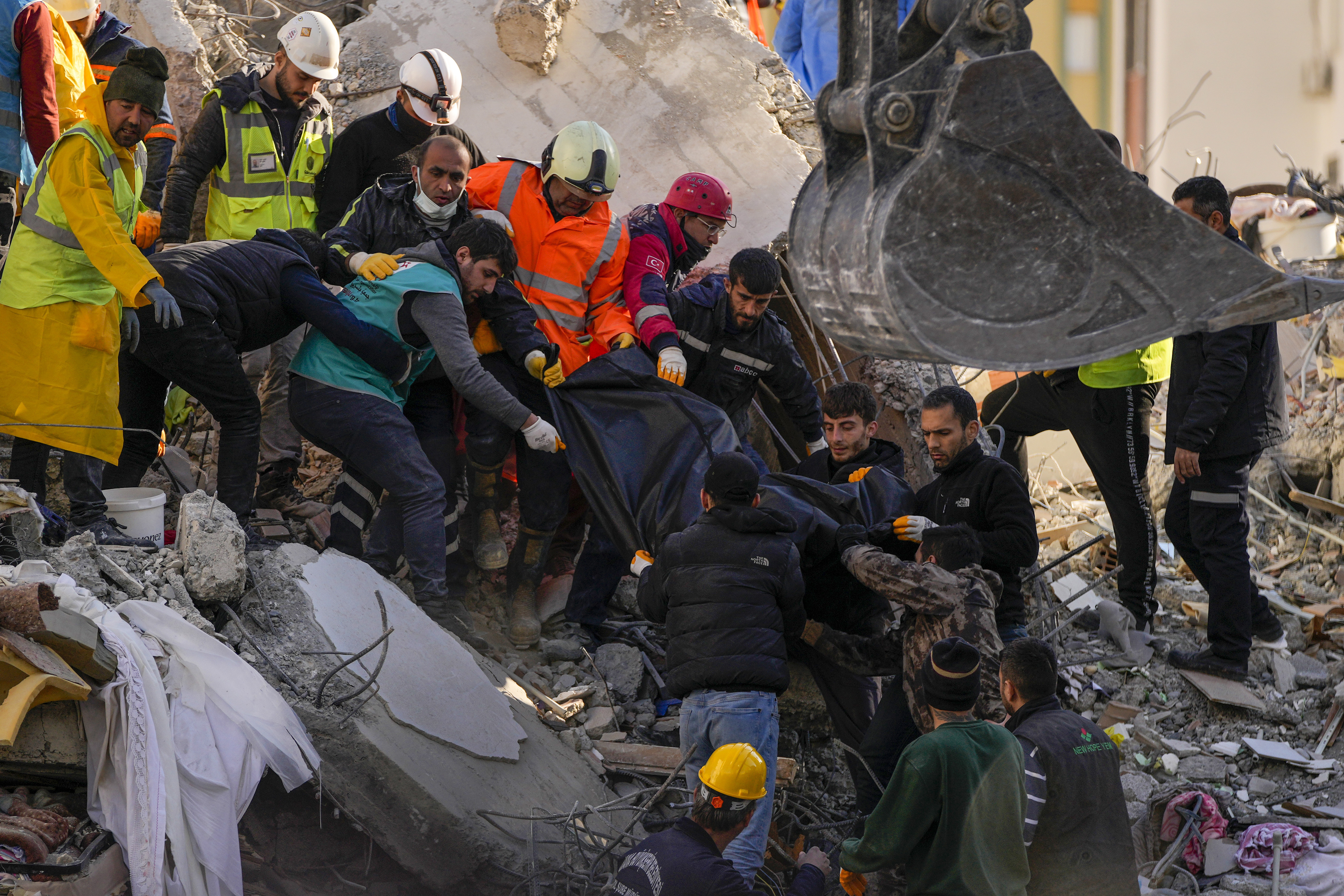 Emergency team members carry a body of a person found in the rubble of a destroyed building in Adana, Turkey, Tuesday, Feb. 7, 2023. Rescuers raced Tuesday to find survivors in the rubble of thousands of buildings brought down by a powerful earthquake and multiple aftershocks that struck eastern Turkey and neighboring Syria. (AP Photo/Francisco Seco)