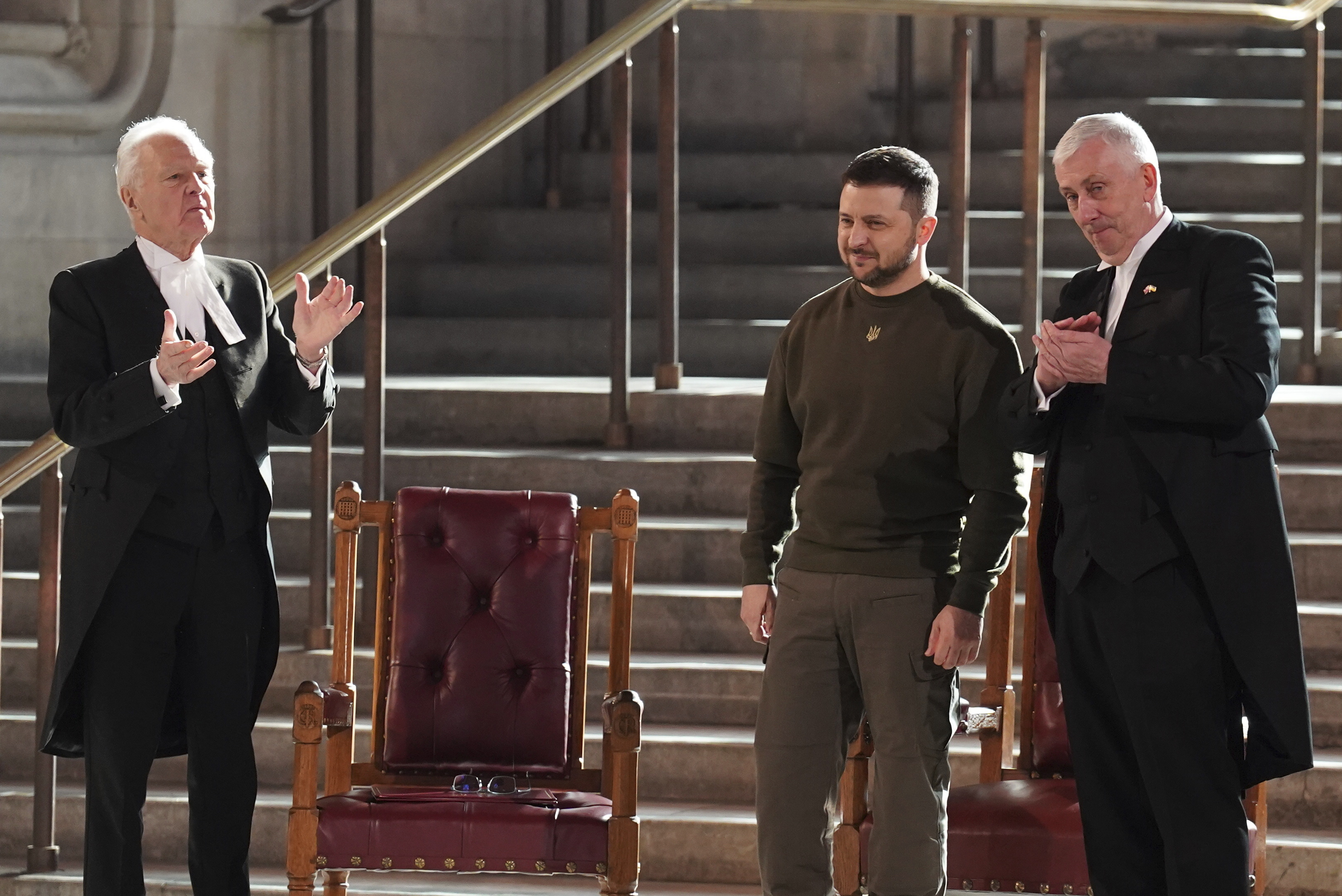 Ukrainian President Volodymyr Zelenskyy is applauded by Speaker of the House of Commons, Sir Lindsay Hoyle, right, and Speaker of the House of Lords Lord McFall, left, following his address to parliamentarians in Westminster Hall, London, during his first visit to the UK since the Russian invasion of Ukraine.Wednesday Feb. 8, 2023. (Stefan Rousseau/pool photo via AP)