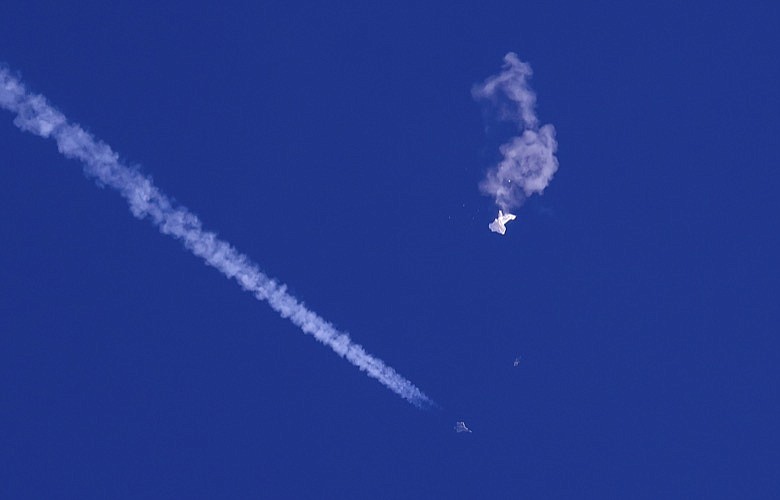 In this photo provided by Chad Fish, the remnants of a large balloon drift above the Atlantic Ocean, just off the coast of South Carolina, with a fighter jet and its contrail seen below it, Feb. 4, 2023. China on Thursday, Feb. 9, 2023, said U.S. accusations that a downed Chinese balloon was part of an extensive surveillance program amount to “information warfare against China.” (Chad Fish via AP, File)