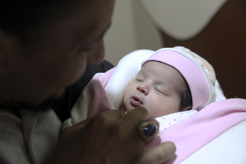 Khalil al-Sawadi looks at Afraa, a baby girl who was born under the rubble caused by an earthquake that hit Syria and Turkey, in the town of Jinderis, Aleppo province, Syria, Monday, Feb. 20, 2023. Afraa left the hospital and has gone to her new home with her paternal aunt's family Monday, Feb. 20. (AP Photo/Ghaith Alsayed)