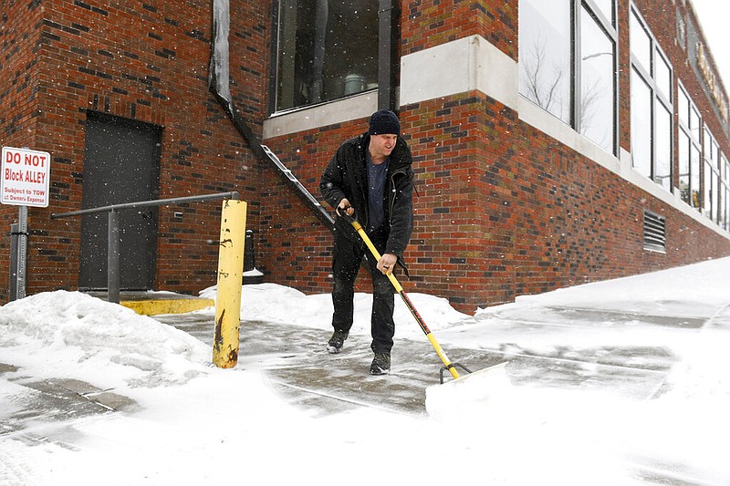 David Smith shovels the sidewalk as the first snow falls ahead of a winter storm on Tuesday, Feb. 21, 2023, in Sioux Falls, S.D. (Erin Woodiel/The Argus Leader via AP)