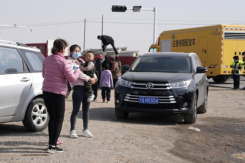 People gather Thursday at a checkpoint along a road leading to the site of a collapsed open pit mine in Alxa League in northern China’s Inner Mongolia Autonomous Region. Video at arkansasonline.com/224alxa/.
(AP/Ng Han Guan)