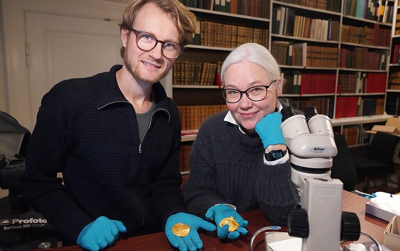 Experts Krister Vasshus, left, and Lisbeth Imer hold golden bracteates unearthed in Vindelev, Denmark in late 2020. (John Fhær Engedal Nissen, The National Museum of Denmark via AP)