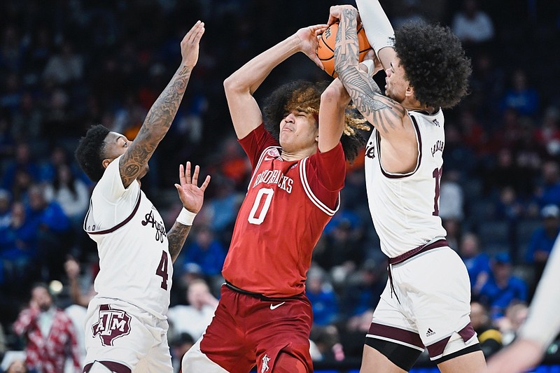 Arkansas guard Anthony Black (0) defends the ball from a pair of Texas A&M defenders, Friday, March 10, 2023 during the second half of the 2023 SEC Men’s Basketball Tournament quarterfinal at Bridgestone Arena in Nashville, Tenn.