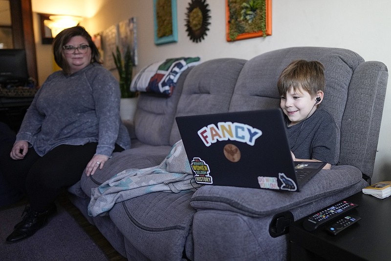 Jessica Blalack, left, watches as her son Phoenix Blalack, 6 , works with a tutor on his laptop in his Indianapolis home, Tuesday, March 7, 2023. (AP Photo/AJ Mast)