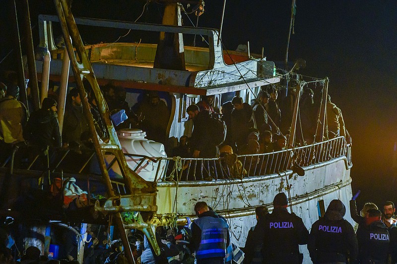 Police check a fishing boat with some 500 migrants in the southern Italian port of Crotone, early Saturday, March 11, 2023. The Italian coast guard was responding to three smugglers boats carrying more than 1,300 migrants “in danger” off Italy’s southern coast, officials said Friday. Three small coast guard boats were rescuing a boat with 500 migrants about 70 nautical miles off the Calabria region, which forms the toe of the Italian boot.  (AP Photo/Valeria Ferraro)