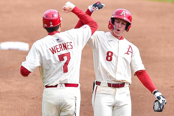 Arkansas outfielder Jace Bohrofen (8) celebrates with first-base coach Bobby Wernes after hitting a lead-off double, Sunday, March 12, 2023, during the second inning between the Razorbacks and the Louisiana Tech Bulldogs at Baum-Walker Stadium in Fayetteville.