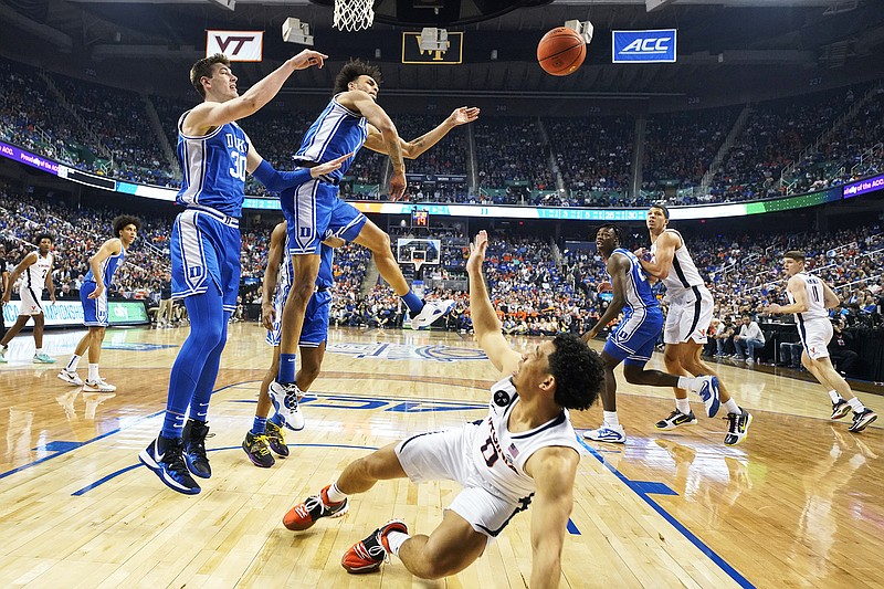 Virginia's Kihei Clark has his shot blocked by Duke's Dereck Lively II (1) as Duke's Kyle Filipowski (30) looks on Saturday during the Atlantic Coast Conference Tournament championship game in Greensboro, N.C. (Associated Press)