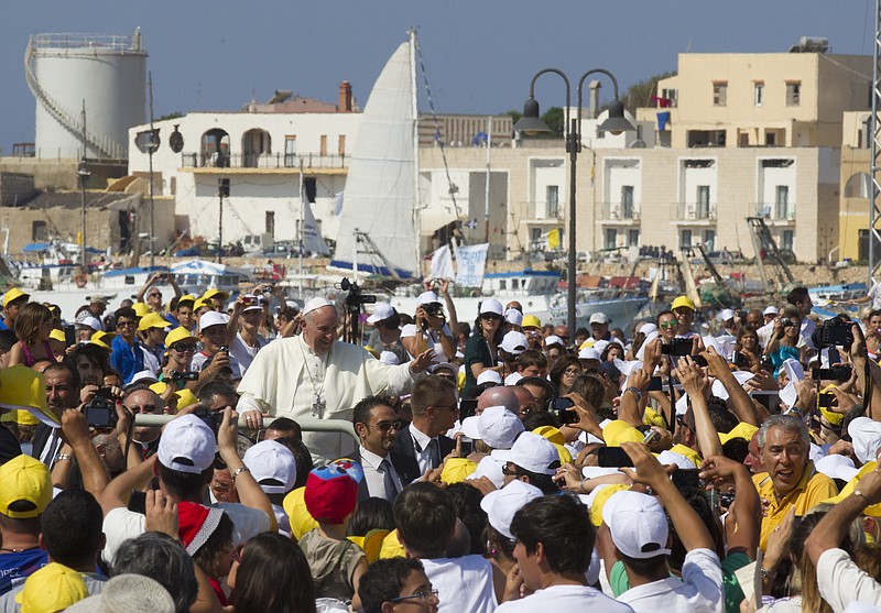 FILE - Pope Francis waves to faithful as he is driven through the crowd during his visit to the island of Lampedusa, southern Italy, on July 8, 2013, where he denounced the "globalization of indifference" that greets migrants who risk their lives trying to reach Europe. Pope Francis' first 10 years as pope have been marked by several historic events, as well as several unplanned moments or comments that nevertheless helped define the contours and priorities of history's first Latin American pope. (AP Photo/Alessandra Tarantino, File)