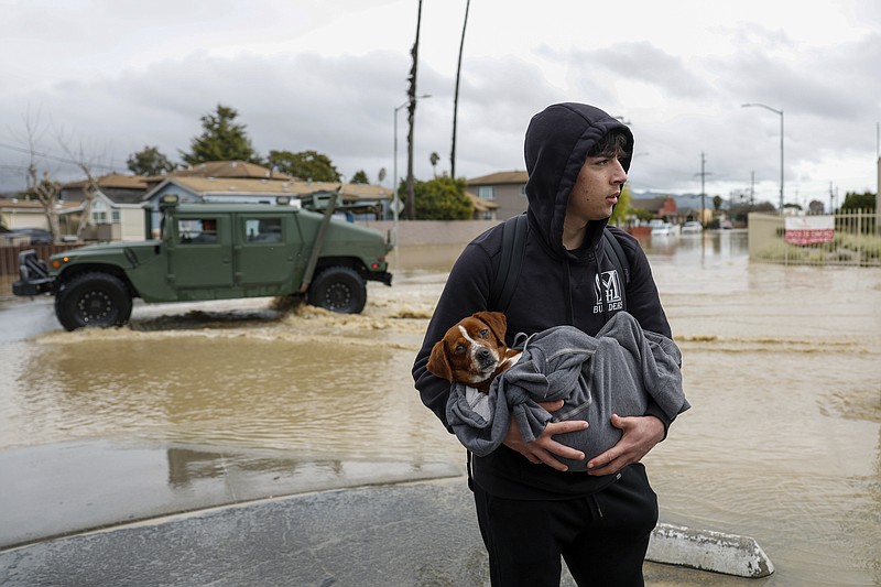 FILE - Esteban Sepulveda holds his dog Milo while leaving his home in Pajaro Valley, Calif., March 12, 2023. Record snowfall and rain have helped to loosen drought’s grip on parts of the western U.S. as national forecasters and climate experts warned Thursday, March 16, that some areas should expect more flooding as the snow begins to melt. (Shae Hammond/Bay Area News Group via AP, File)